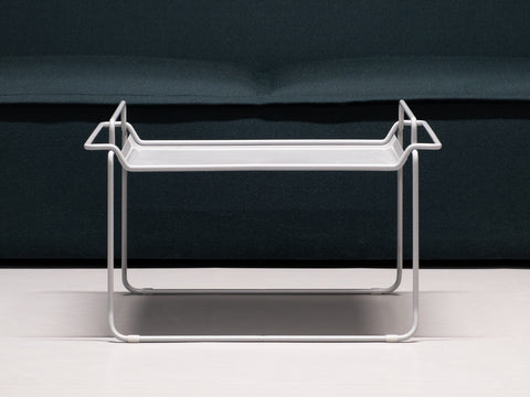 Tangens Tablett-Tisch in grau vor einer dunkelgrünen Couch